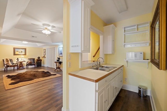 kitchen featuring white microwave, a sink, white cabinetry, visible vents, and dark wood-type flooring