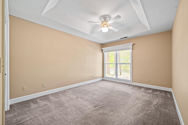 unfurnished room with ceiling fan, a raised ceiling, and carpet floors