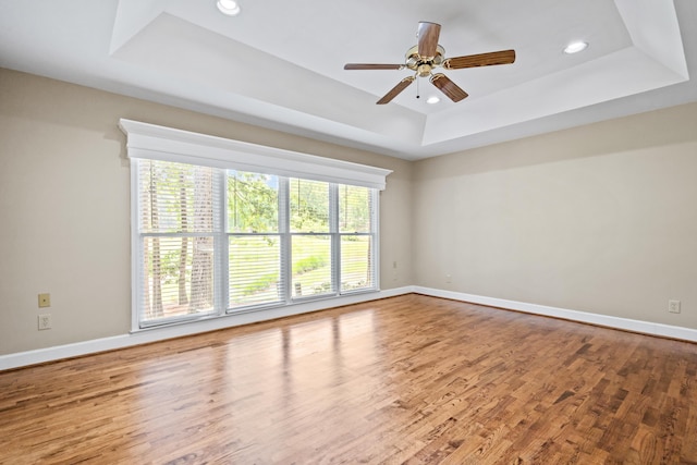 unfurnished room featuring wood-type flooring, ceiling fan, and a tray ceiling