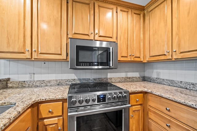 kitchen with tasteful backsplash, appliances with stainless steel finishes, and light stone countertops