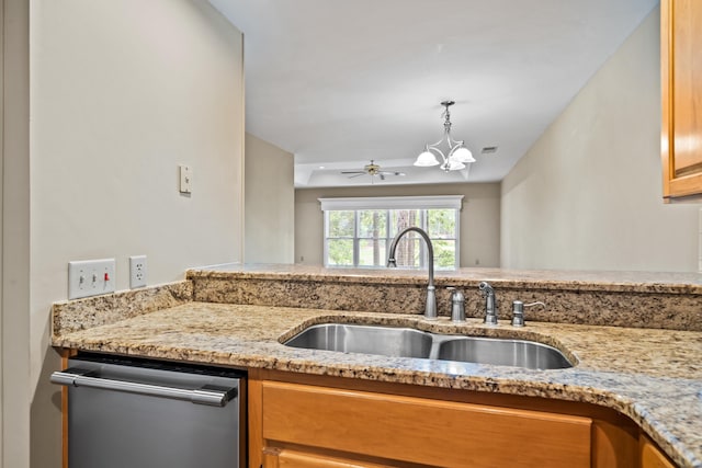 kitchen with pendant lighting, sink, light stone counters, ceiling fan with notable chandelier, and stainless steel dishwasher