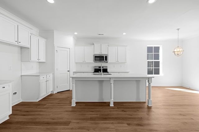 kitchen with stainless steel microwave, dark wood-style flooring, a kitchen island with sink, white cabinetry, and a sink