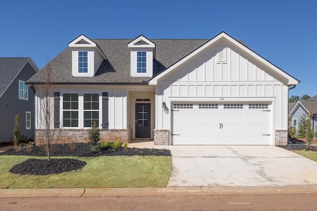 view of front facade with an attached garage, brick siding, a shingled roof, concrete driveway, and board and batten siding