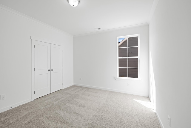 unfurnished bedroom with crown molding, a closet, visible vents, carpet flooring, and baseboards