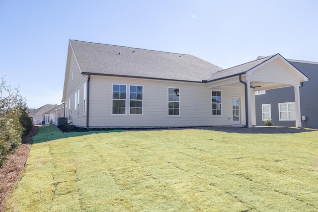 back of house with a yard, roof with shingles, and cooling unit