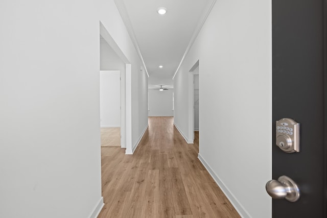 hall with light wood-type flooring, crown molding, baseboards, and recessed lighting