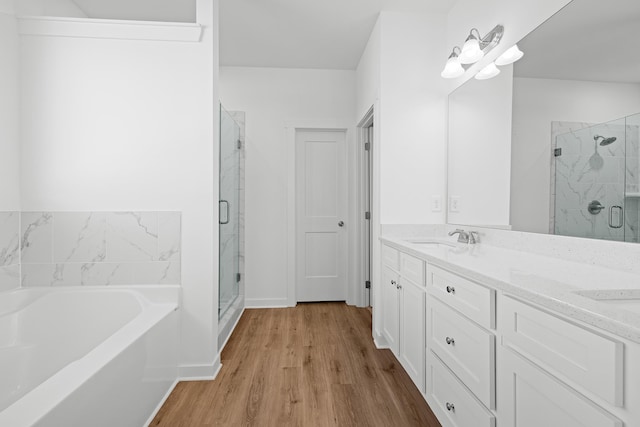 bathroom featuring double vanity, a garden tub, a sink, and a stall shower