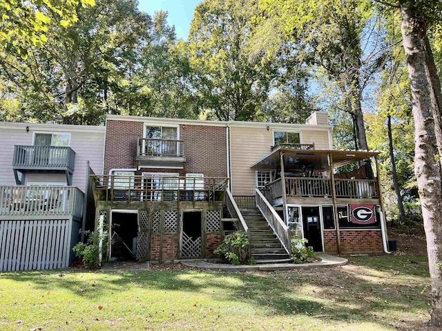 rear view of house featuring a wooden deck, a lawn, and a balcony