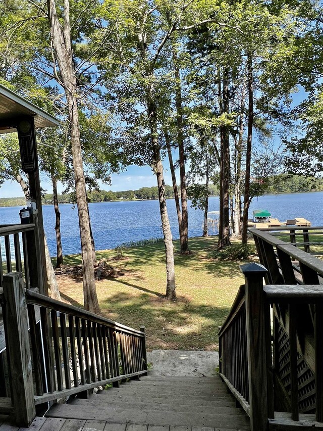 deck with a water view and a lawn