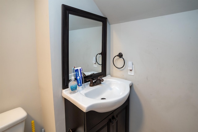 bathroom featuring vanity, vaulted ceiling, and toilet