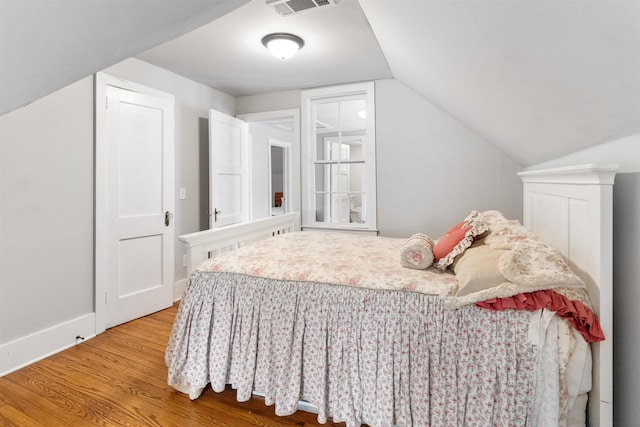 bedroom featuring hardwood / wood-style flooring and lofted ceiling