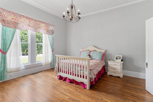 bedroom with hardwood / wood-style flooring, crown molding, and a notable chandelier