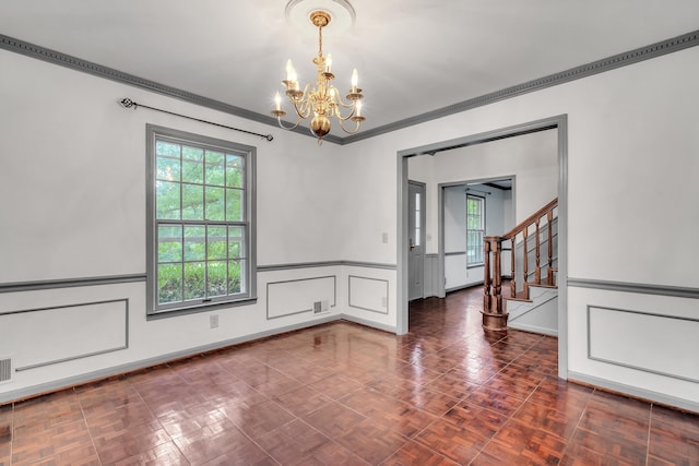 spare room with dark parquet flooring, ornamental molding, and an inviting chandelier