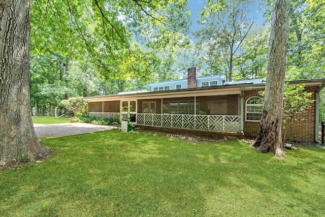 rear view of house with a lawn and a sunroom