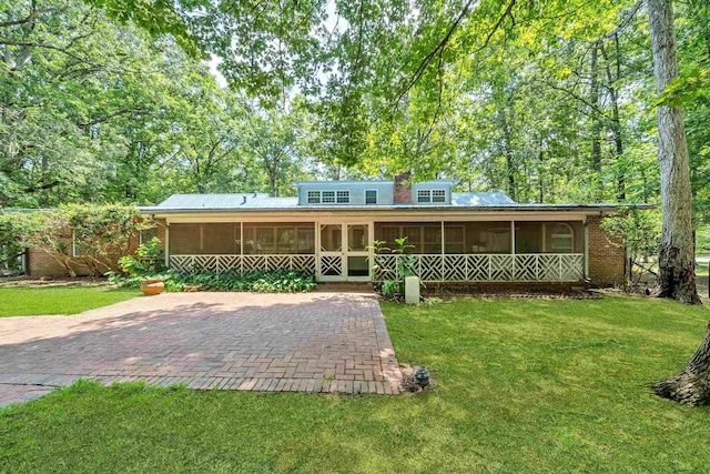 back of property with a lawn, a sunroom, and a patio