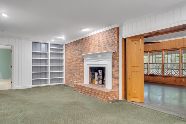 unfurnished living room with built in shelves, ornamental molding, a brick fireplace, and dark colored carpet