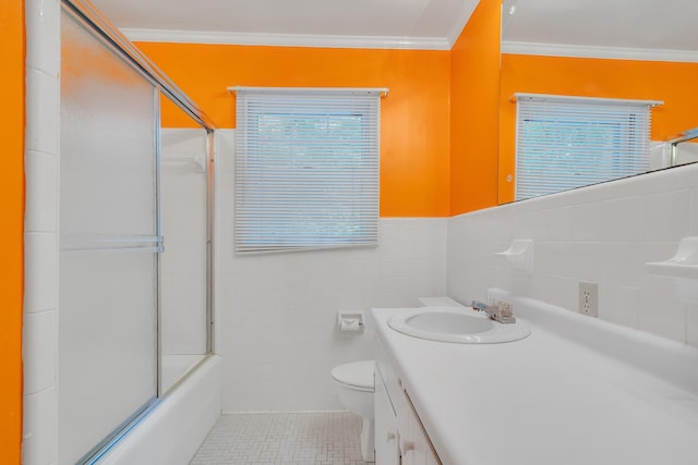 full bathroom featuring crown molding, tile walls, bath / shower combo with glass door, vanity, and toilet