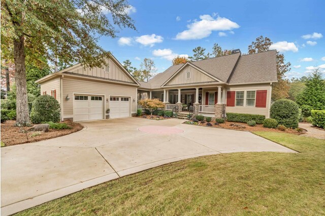 craftsman house with a garage, a front yard, and a porch