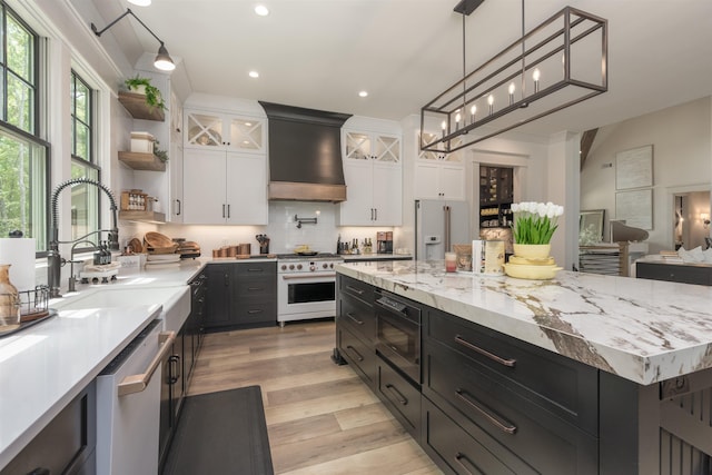 kitchen with pendant lighting, premium range hood, backsplash, high quality appliances, and white cabinets