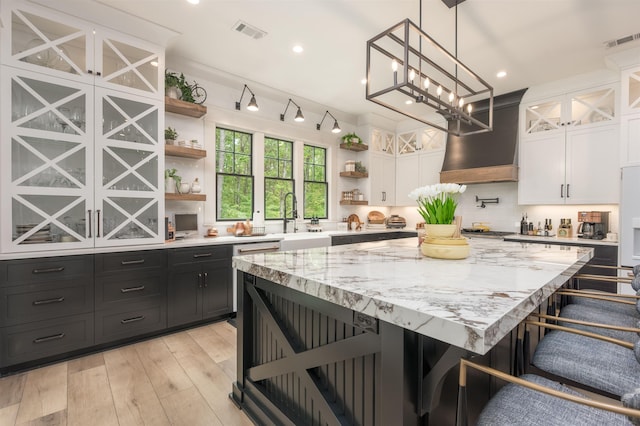 kitchen featuring white cabinetry, a kitchen breakfast bar, decorative light fixtures, and custom exhaust hood