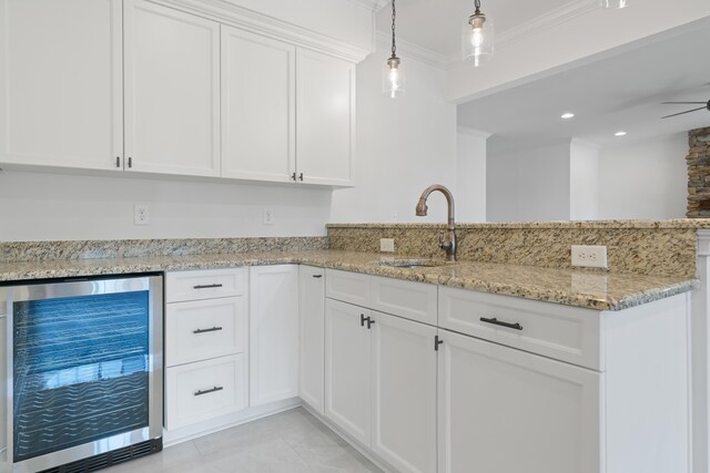 kitchen with sink, white cabinetry, ornamental molding, pendant lighting, and beverage cooler