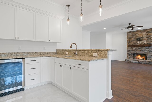 kitchen with sink, kitchen peninsula, beverage cooler, and white cabinets