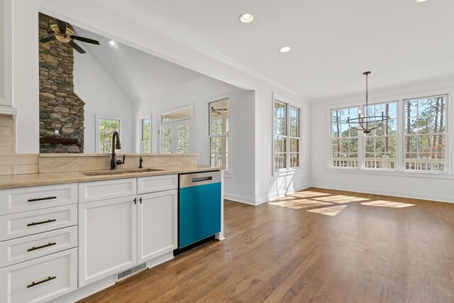 kitchen featuring hanging light fixtures, dishwasher, sink, and white cabinets