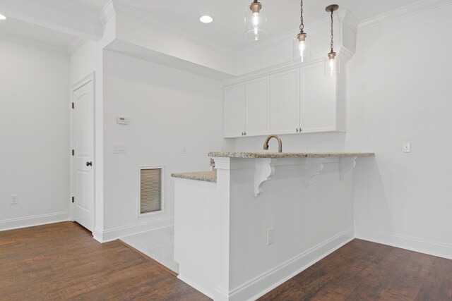 kitchen with hanging light fixtures, ornamental molding, dark hardwood / wood-style floors, and white cabinets