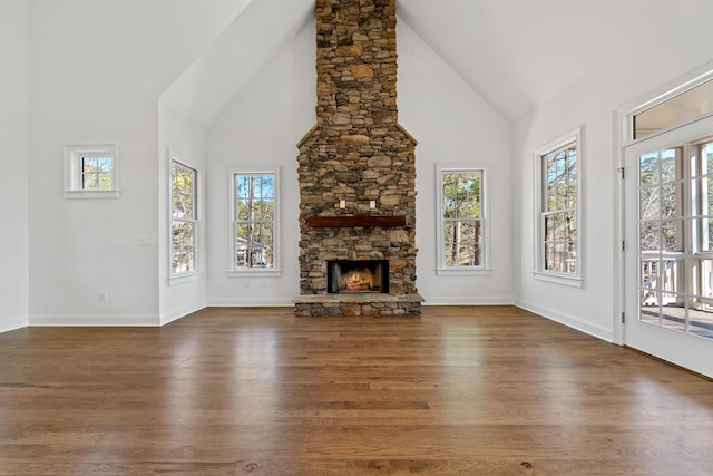 unfurnished living room with a fireplace, high vaulted ceiling, dark hardwood / wood-style floors, and a healthy amount of sunlight