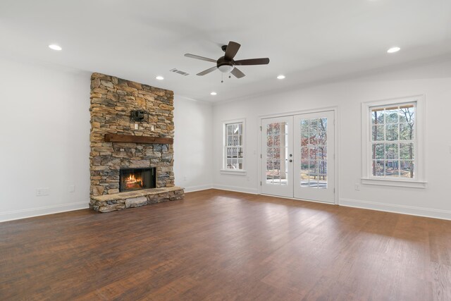 unfurnished living room with a stone fireplace, dark hardwood / wood-style floors, ceiling fan, and french doors