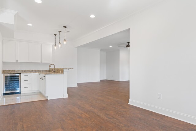 kitchen with wine cooler, white cabinetry, crown molding, decorative light fixtures, and kitchen peninsula