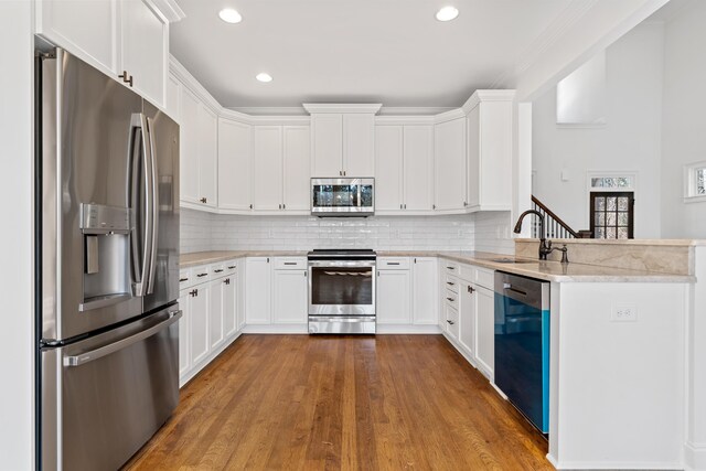 kitchen featuring sink, appliances with stainless steel finishes, white cabinetry, tasteful backsplash, and light stone countertops