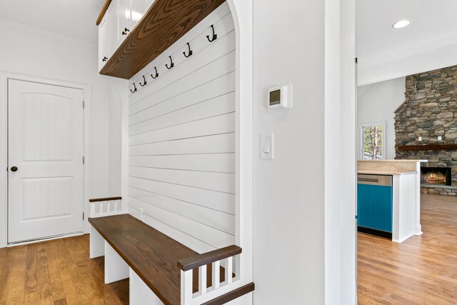 mudroom with crown molding, a fireplace, and light hardwood / wood-style floors