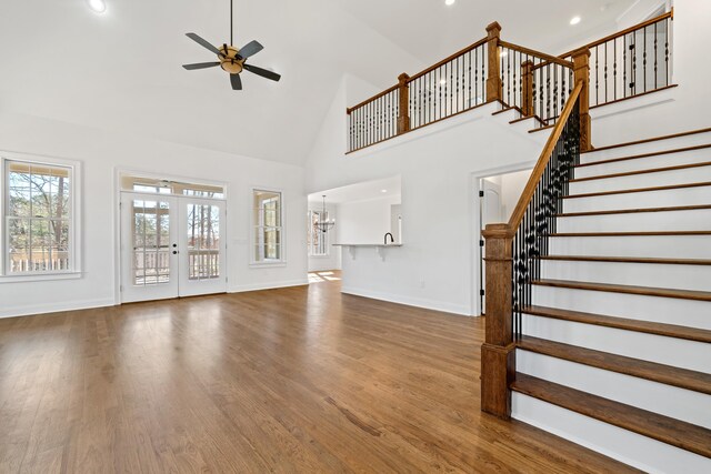 unfurnished living room featuring wood-type flooring, ceiling fan, high vaulted ceiling, and french doors