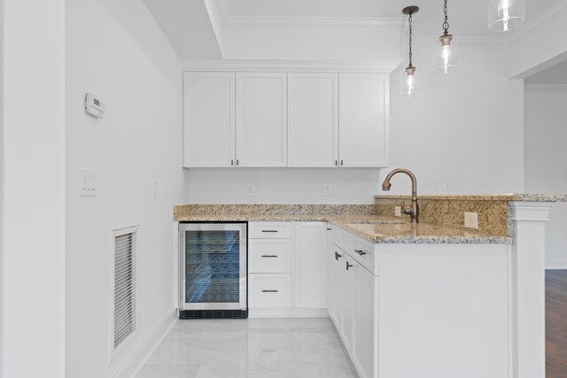 kitchen featuring crown molding, beverage cooler, hanging light fixtures, and white cabinets