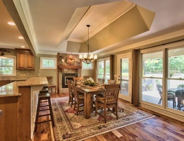 dining room featuring a large fireplace, plenty of natural light, ornamental molding, and dark hardwood / wood-style floors