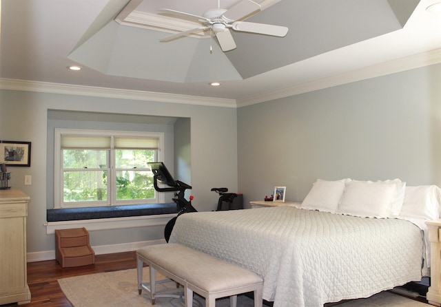 bedroom featuring dark wood-type flooring, ceiling fan, a tray ceiling, and crown molding