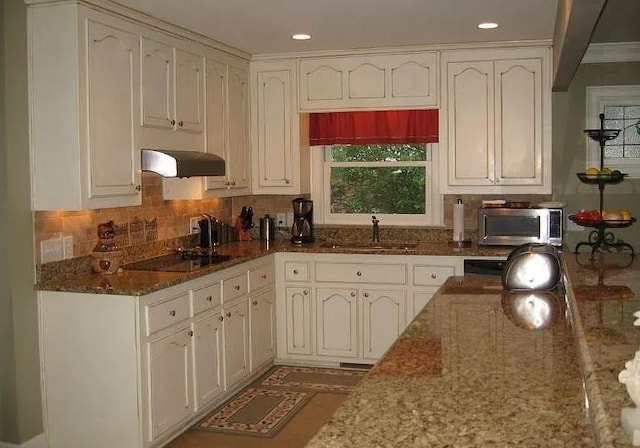 kitchen with white cabinetry, black electric stovetop, sink, and dark stone countertops