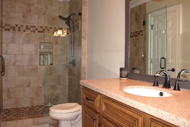 bathroom featuring vanity, a shower with door, and toilet