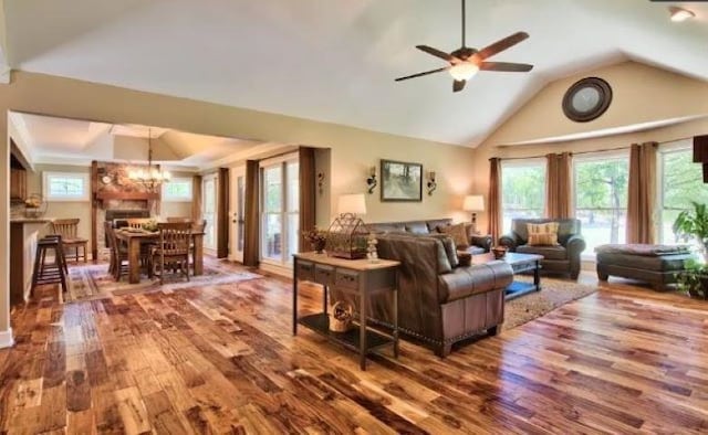 living room with ceiling fan with notable chandelier, lofted ceiling, and hardwood / wood-style floors