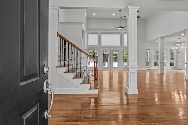 entrance foyer featuring french doors, decorative columns, hardwood / wood-style flooring, a healthy amount of sunlight, and ceiling fan with notable chandelier