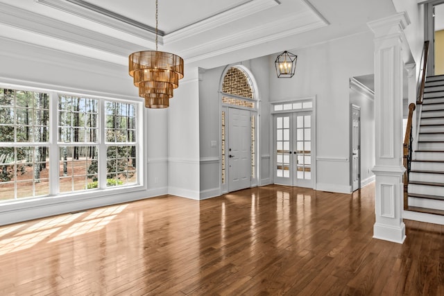 entryway with a raised ceiling, ornamental molding, dark wood-type flooring, and a chandelier