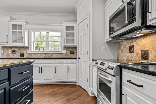 kitchen featuring white cabinetry, sink, dark stone countertops, stainless steel appliances, and light wood-type flooring