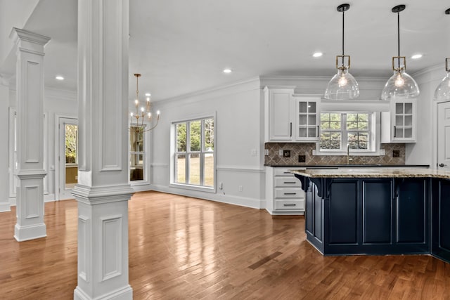 kitchen with decorative columns, white cabinetry, tasteful backsplash, dark stone countertops, and hanging light fixtures