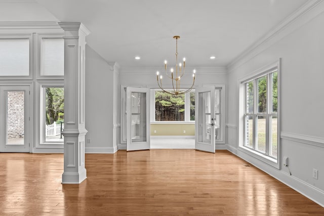 entryway featuring ornate columns, ornamental molding, a notable chandelier, and light hardwood / wood-style floors