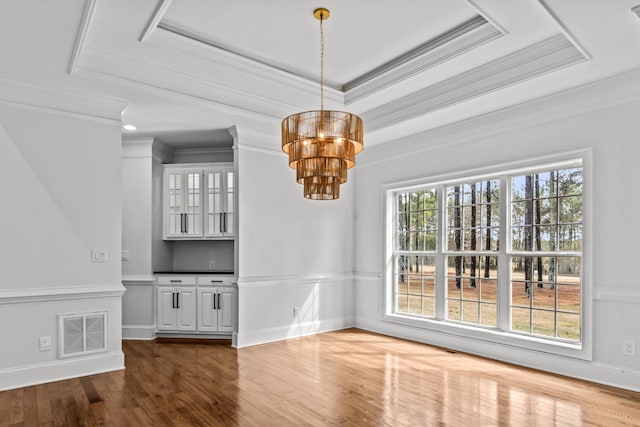 unfurnished dining area featuring crown molding, a tray ceiling, dark hardwood / wood-style flooring, and a notable chandelier