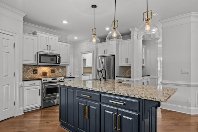 kitchen featuring stainless steel appliances, hanging light fixtures, a center island with sink, and white cabinets