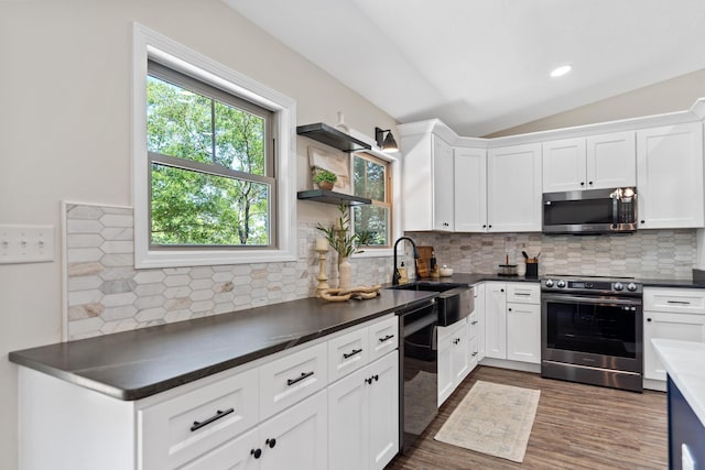 kitchen featuring lofted ceiling, a sink, tasteful backsplash, appliances with stainless steel finishes, and white cabinetry