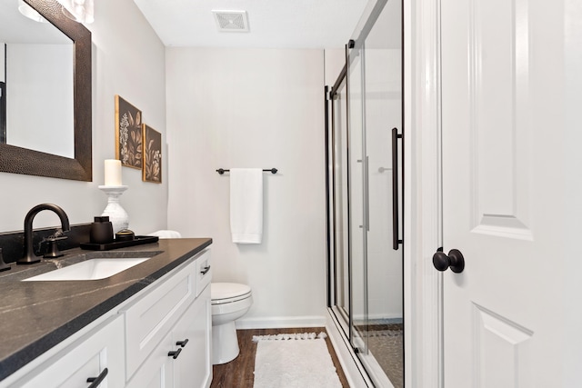 bathroom with toilet, a stall shower, baseboards, visible vents, and vanity