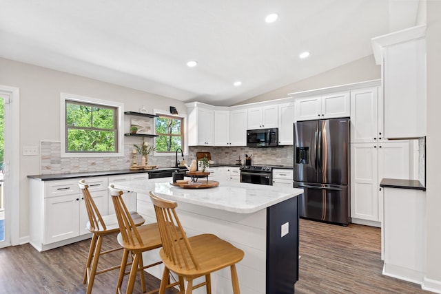 kitchen with stainless steel fridge, vaulted ceiling, electric range, and tasteful backsplash